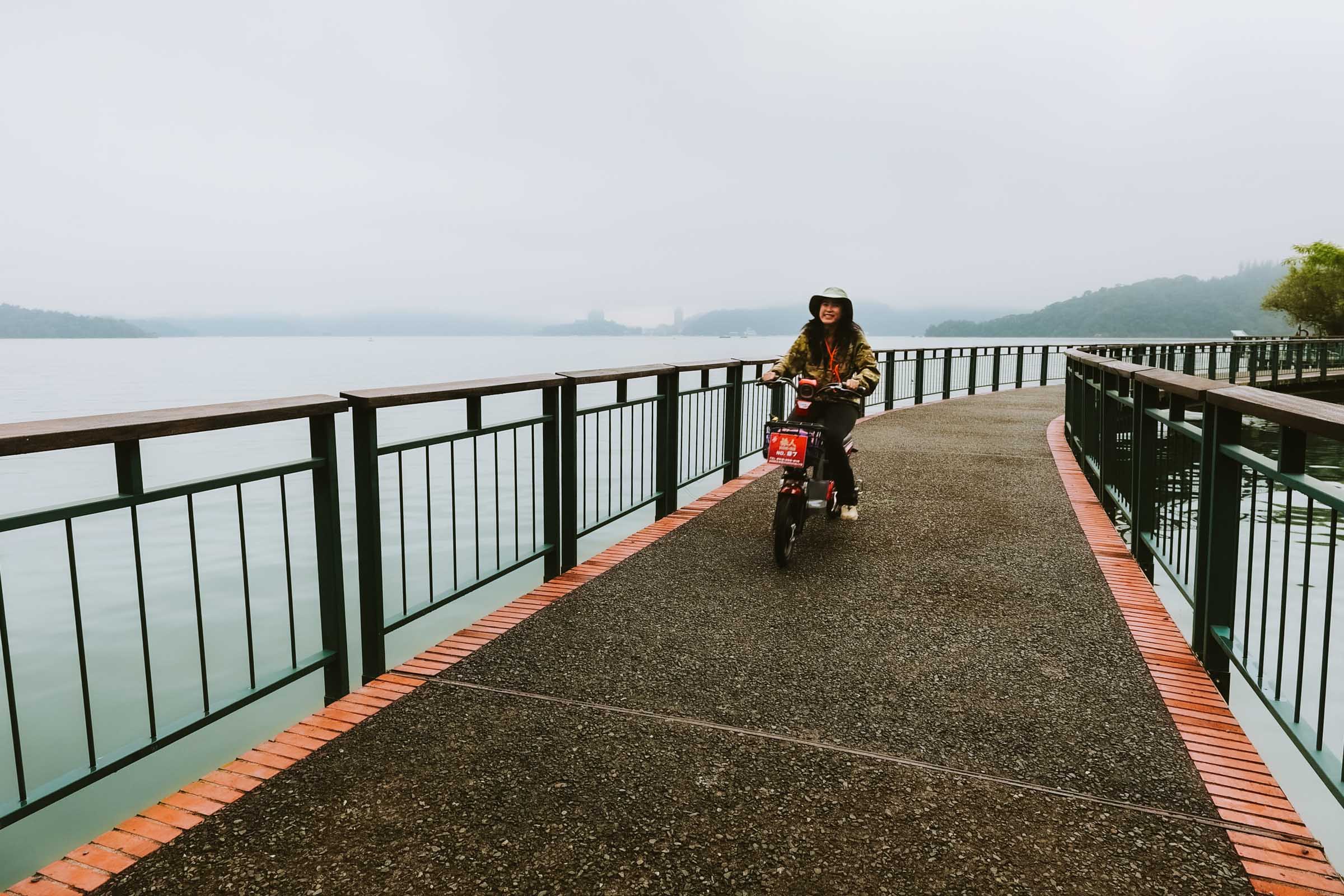 Cyclist riding near Sun Moon Lake with reflections